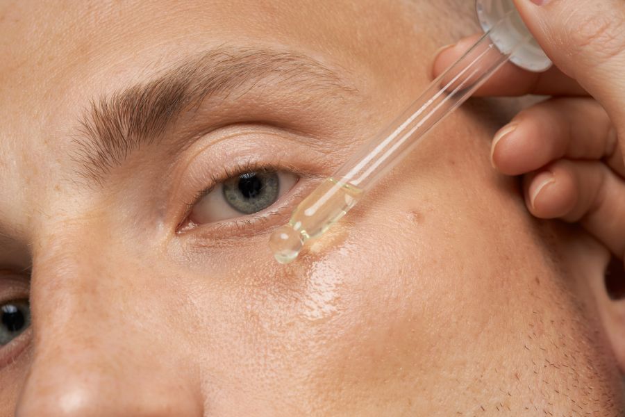closeup of dropper putting oil on cheek